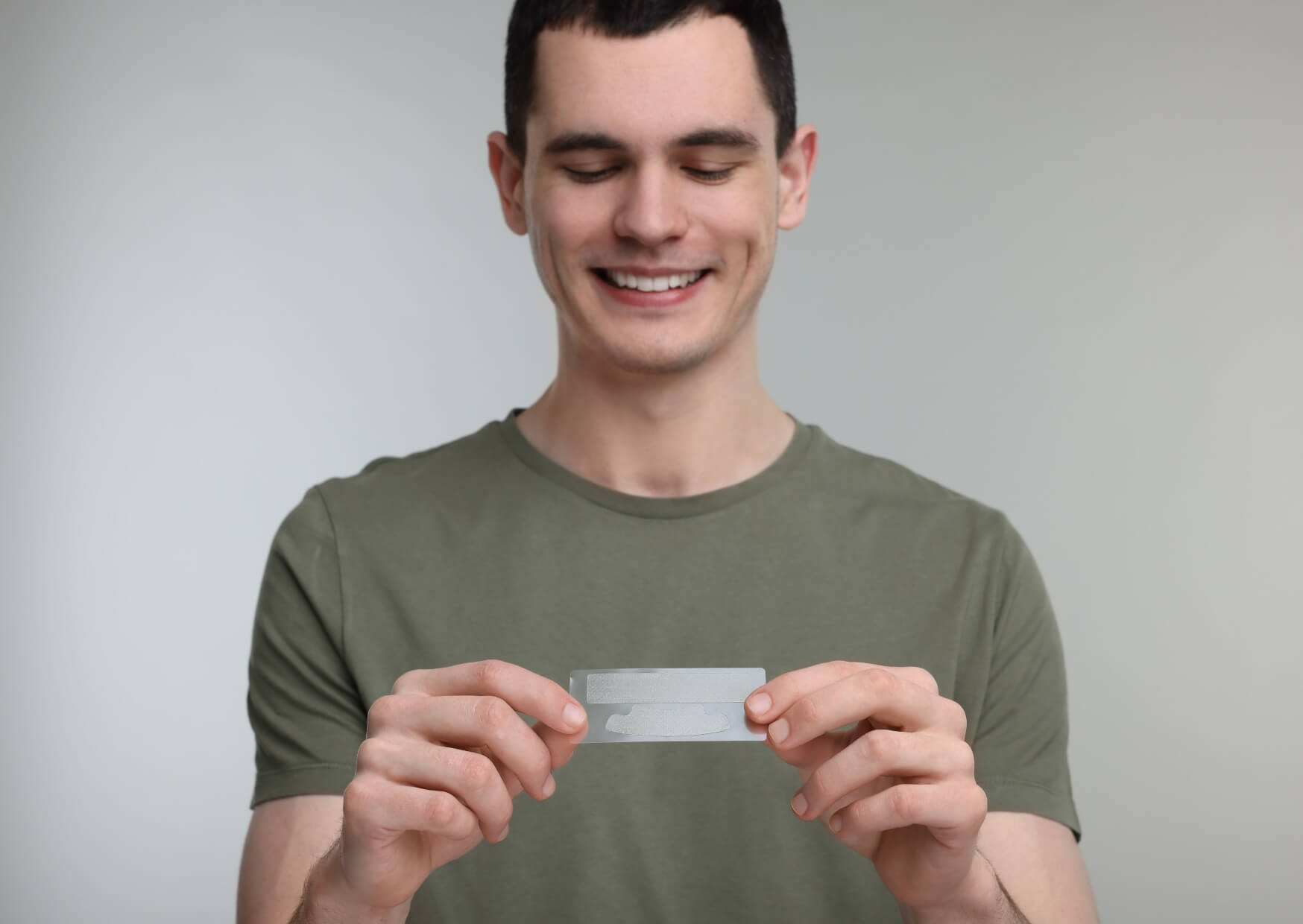 Person holding teeth whitening strips before use, illustrating at-home teeth whitening strip effectiveness.