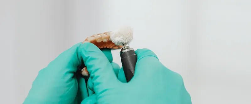 a hand with gloves modeling a denture