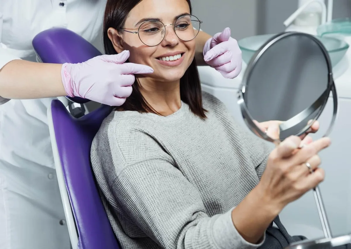 Patient viewing her restored smile while discussing full mouth dental implants cost with a dental professional.