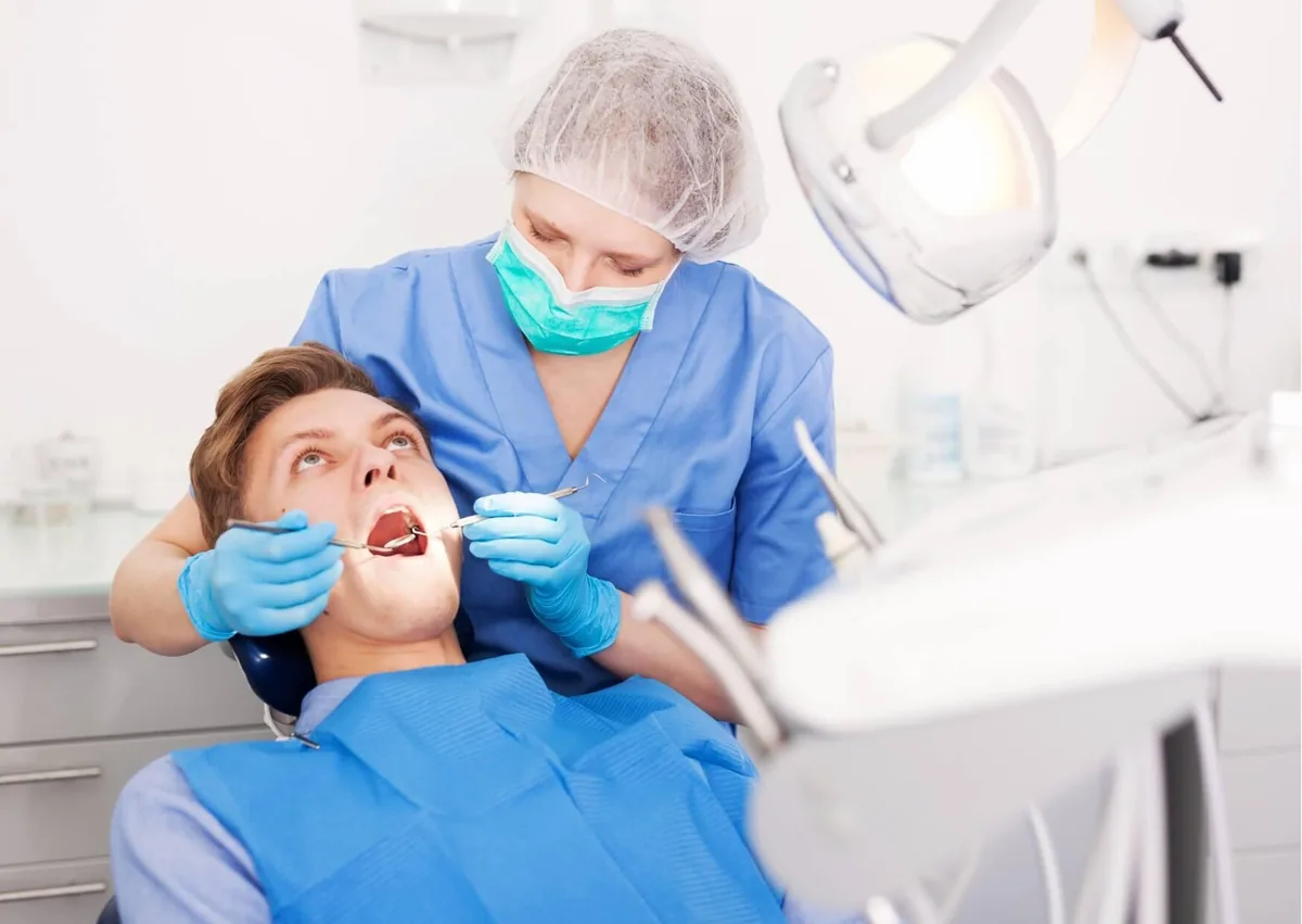 Dentist examining a patient’s mouth to assess a canker sore and how long it may take to heal.