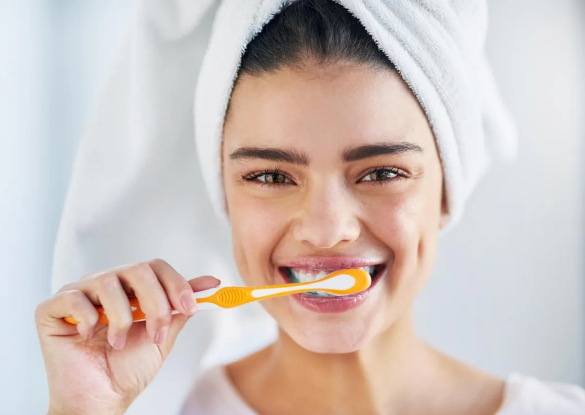 Woman brushing her teeth to remove plaque and maintain good oral hygiene at home.