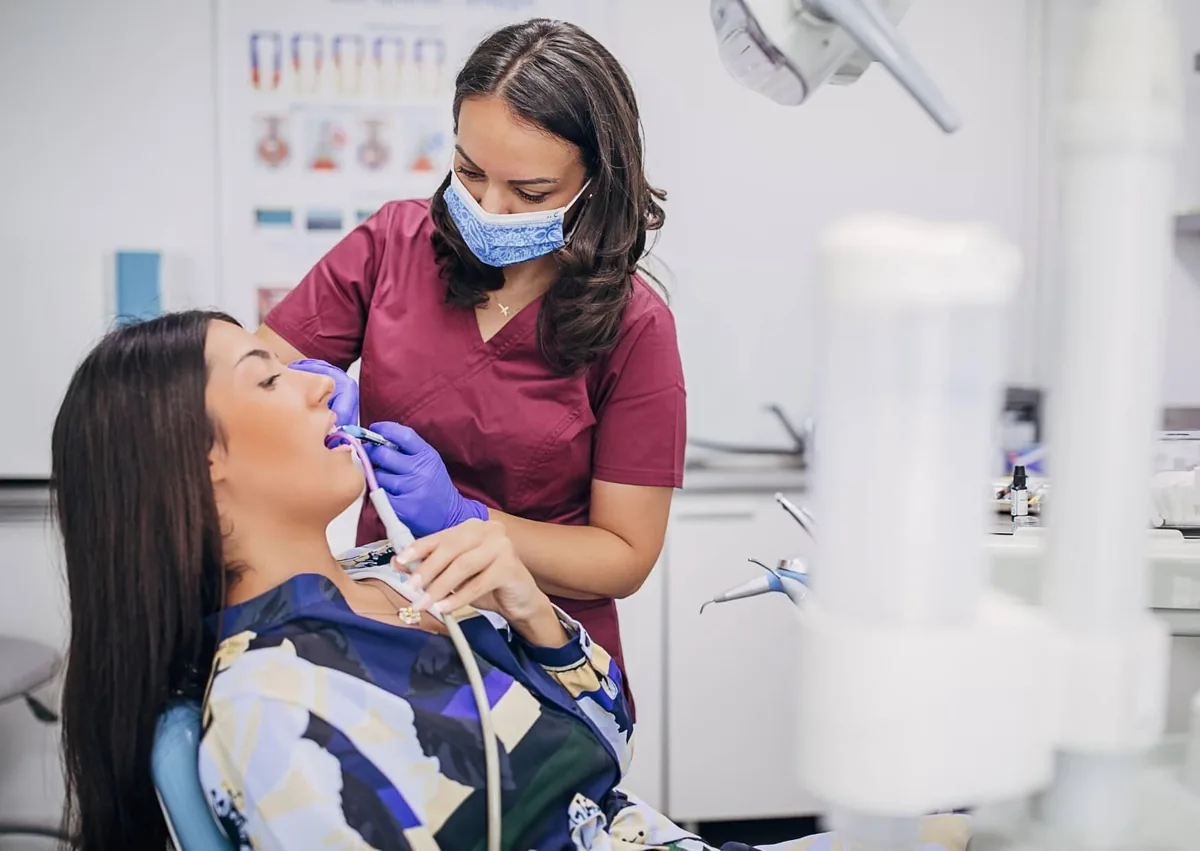 Dental professional removing plaque from a patient’s teeth during a professional cleaning.